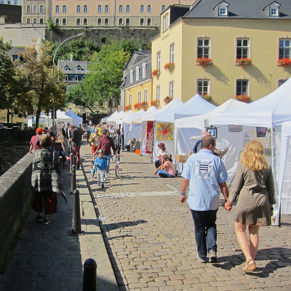 image: lots of gazebos sitting in a row on a cobblestone bridge under the september sun
